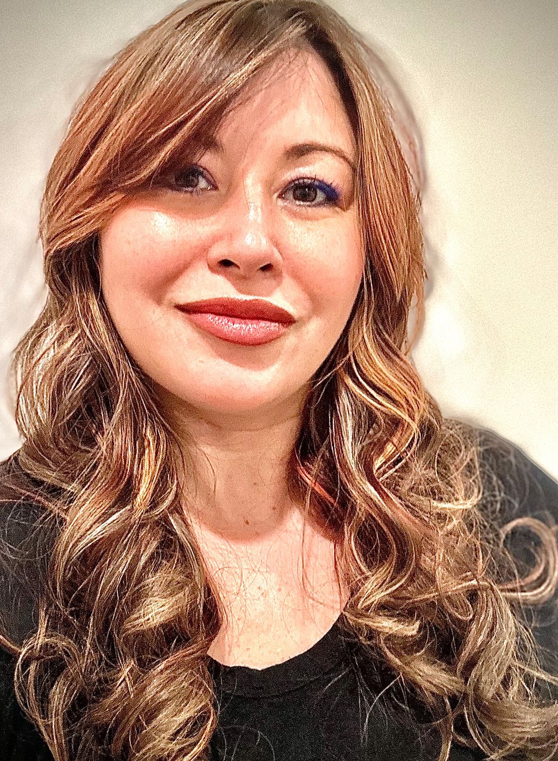 Woman with wavy hair smiling at the camera.
