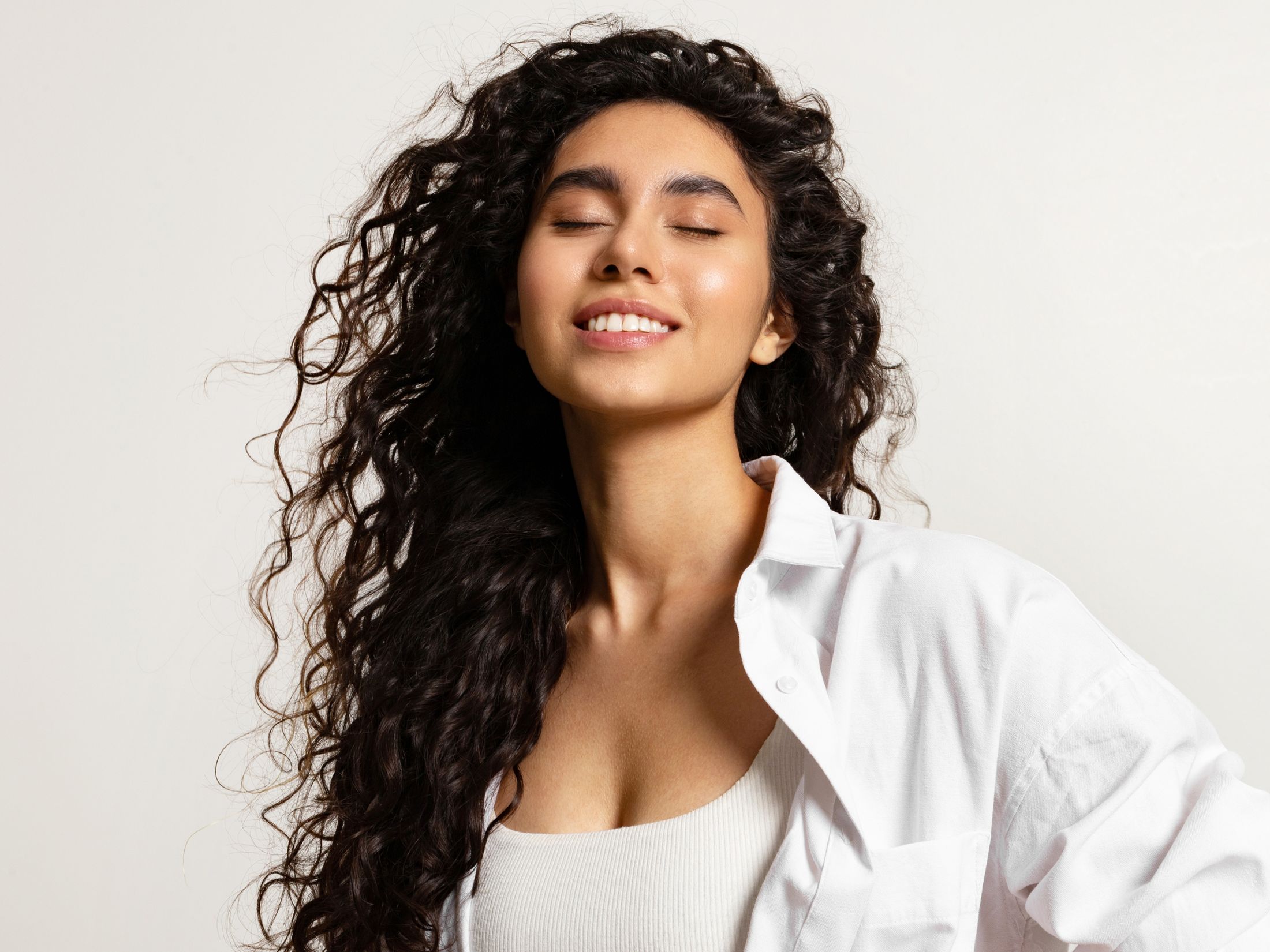 Smiling person with curly hair and white shirt.