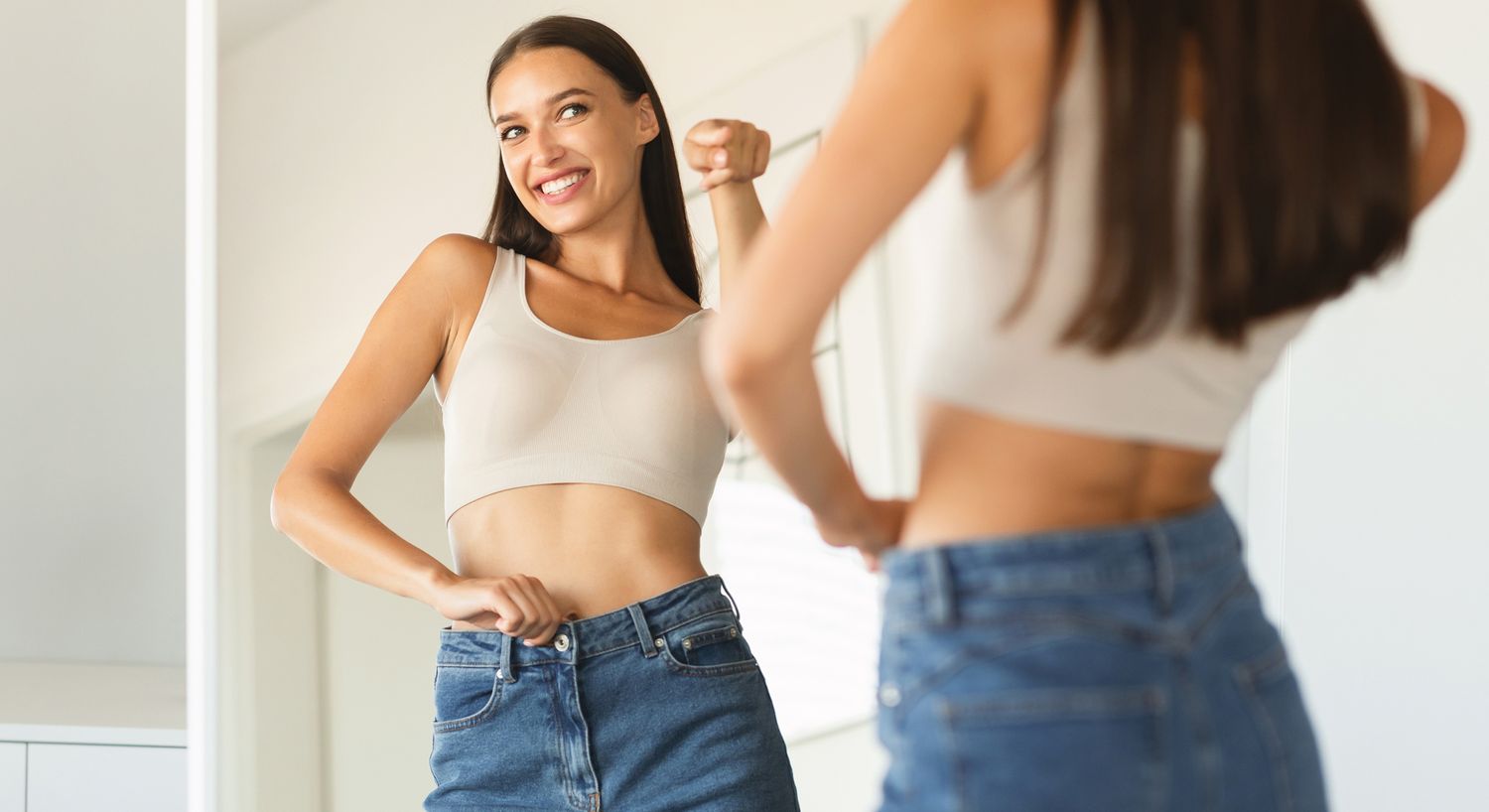Woman admiring outfit in front of mirror.